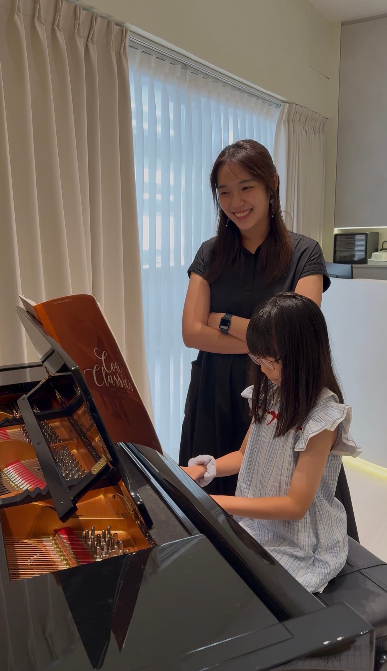 Teacher Sarah guiding a young student at the grand piano